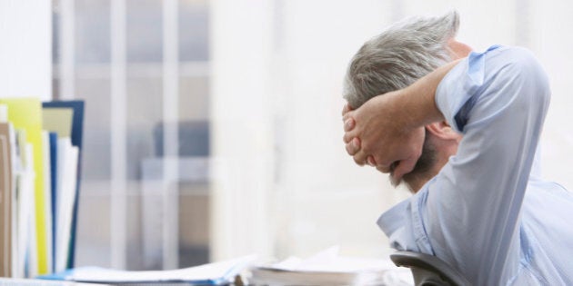 Business man with hands behind head in office