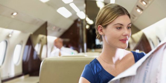 Businesswoman reading newspaper in airplane
