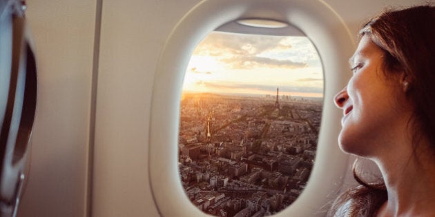 Smiling woman enjoying Paris from the airplane window