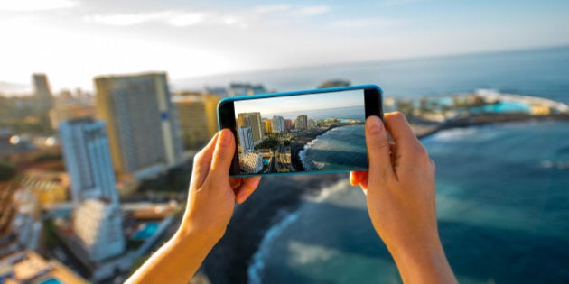 Femaile tourist photographing with smartphone Puerto de la Cruz City on Tenerife island