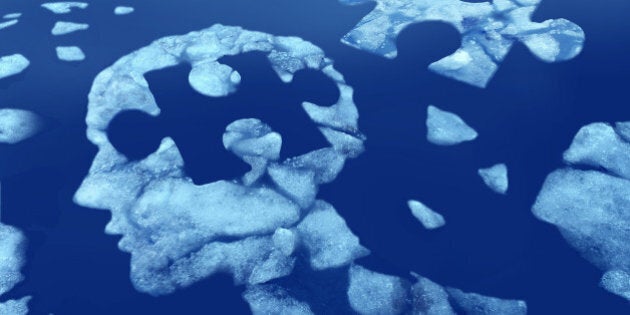 Puzzle head idea and concept as a human face profile made from floating icefloating away in water with a jigsaw piece cut out on a cold blue arctic background as a mental health symbol.