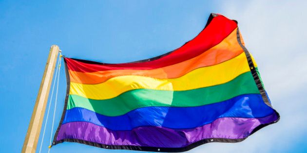 Gay rainbow flags waving over blue sky background
