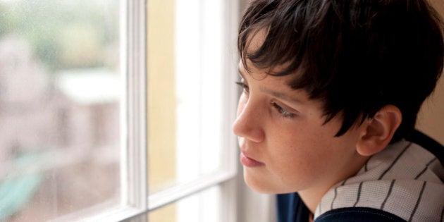 Pensive child looking through a window