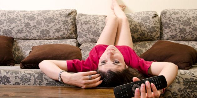 Girl lying facedown watching television alone.