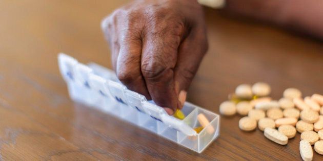Close up of an african seniors hand placing tablets into a tube. Langebaan, Western Cape, South Africa