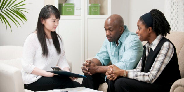 Husband and wife reviewing their finances together in the living room and going over paperwork with their accountant.