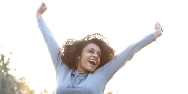 Portrait of a carefree young woman smiling with arms raised