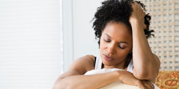 Mid adult woman sitting on the bed and suffering from a headache