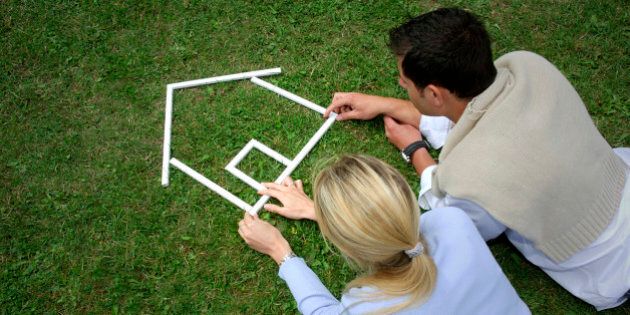 Young couple making house shape with rulers on grass