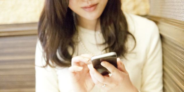 Young woman using smartphone in cafe,mid section