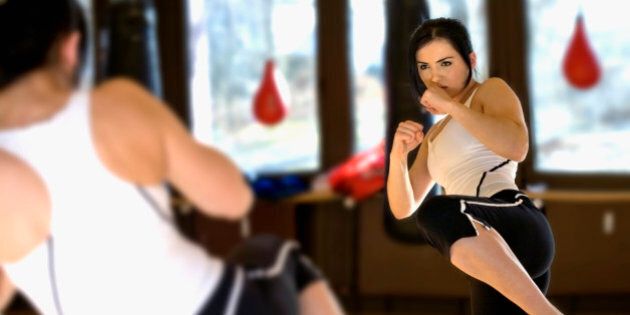 young woman doing kickboxing exercise in front of mirror