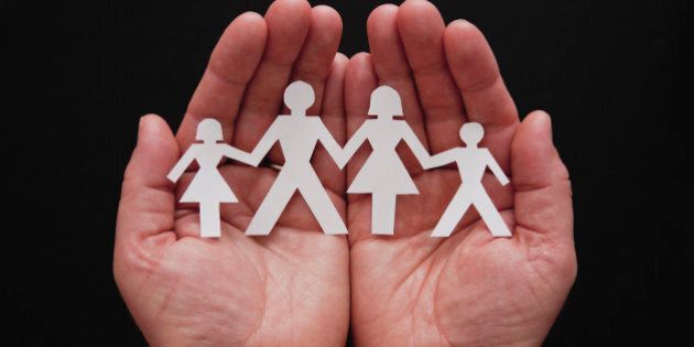 Man's hands holding cut-out representing family