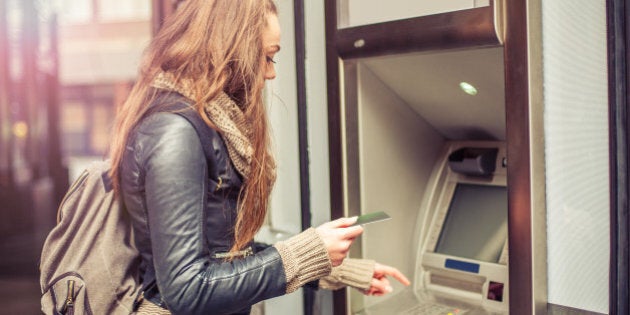 Young woman withdrawing money from credit card at ATM