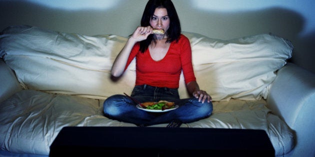 Young woman eating and watching television