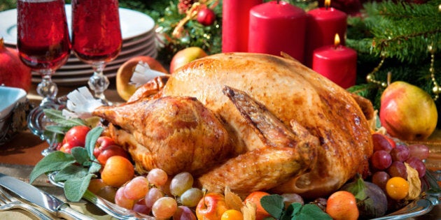 Roasted turkey on holiday table, candles and Christmas tree with ornaments