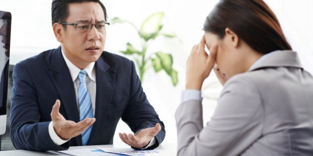 Angry businessman talking to his crying female assistant