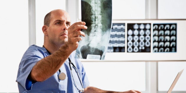 Young doctor examining spinal chord x-ray in radiology clinic office