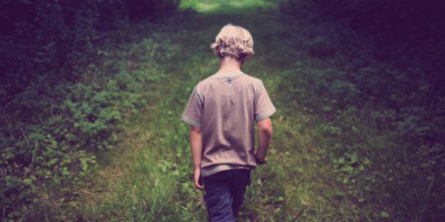 7 year old boy walks down path through woods