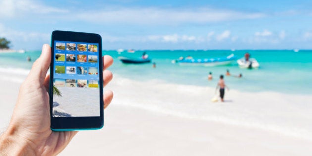 A male person holding a smartphone in the air in the caribbean surrounding of Punta Cana, Dominican Republic.