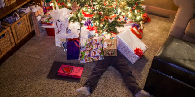 Caucasian boy buried in Christmas gifts