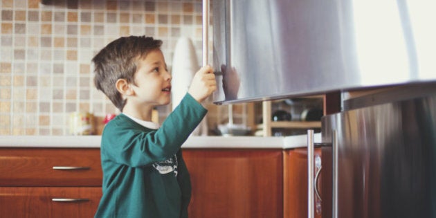 Small boy opening a refrigerator