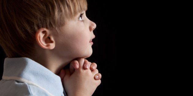 A 5 year old boy saying prayers.