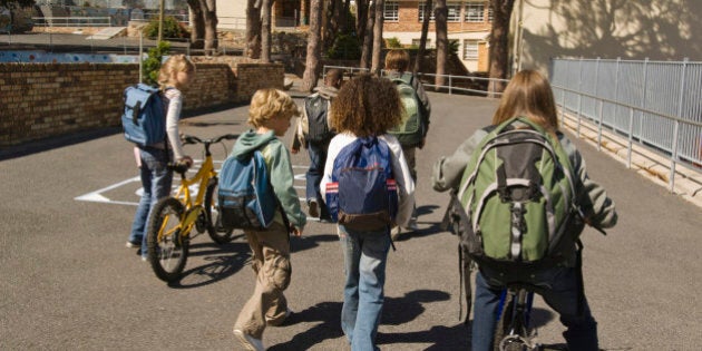 Children walking with bicycles and backpacks