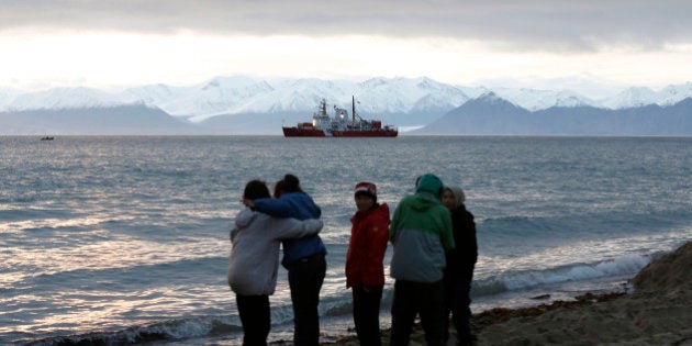 Local children stand on the shore as the Coast Guard ship Des Groseilliers sits in the waters near the Arctic community of Pond Inlet, Nunavut August 23, 2014. Picture taken August 23, 2014. REUTERS/Chris Wattie (CANADA - Tags: MILITARY POLITICS)