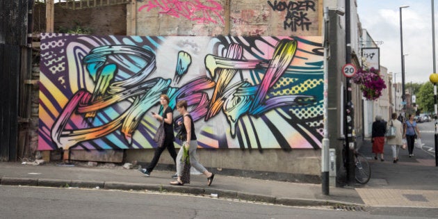 BRISTOL, ENGLAND - JULY 27: People walk past artwork produced as part of the 2016 Upfest on July 27, 2016 in Bristol, England. The annual event, which this year helped celebrate 45 years of the Mr Men and Little Miss book series, started in 2008 and is said to be the largest free street art and graffiti festival in Europe. The festival now attracts more than 300 artists including Inkie, Jody, Pichi & Avo and Leon Keer from 25 countries to paint live on walls and surfaces around Bedminster and Southville areas of the city of Bristol, the hometown of guerrilla artist Banksy. Some of the graffiti art work is painted on moveable boards and temporary hoardings, but murals on some venues and buildings remain all year until the next festival. (Photo by Matt Cardy/Getty Images)