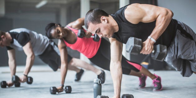 Athletes doing push-ups with dumbbells on floor