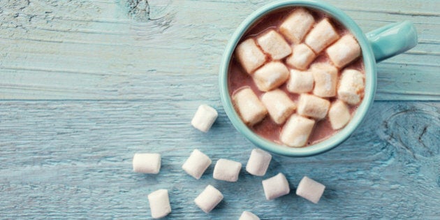 Blue cup of hot cocoa with marshmallows on blue wooden background