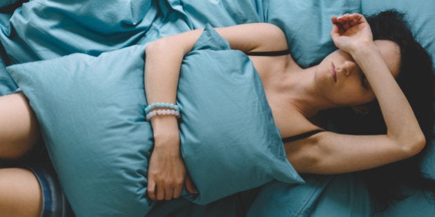 Depressed woman in bed with hand on forehead