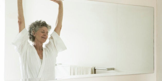 Mature 65 year old woman stretching out in bathroom