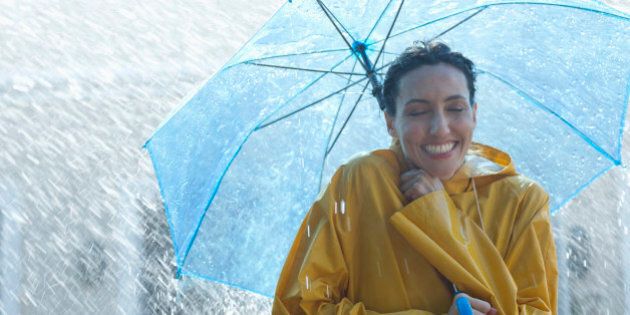 Happy woman under umbrella in rain