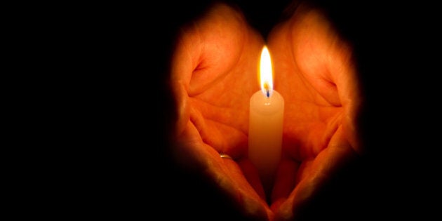 Religious concept. Man hands holding a burning candle on dark background