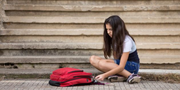 Teenage girl putting notebooks into school bag
