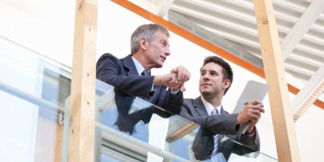 Businessmen having a discussion in walkway of modern office building.