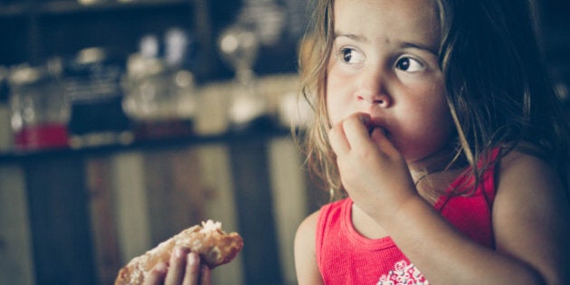 Young girl eating a cannoli in a cafe