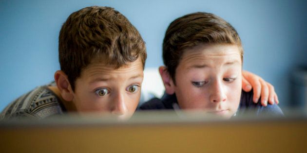 Two surprised boys using a laptop computer.