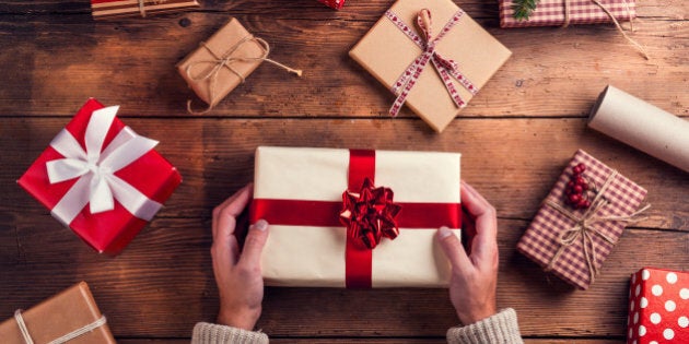 Man holding Christmas presents laid on a wooden table background