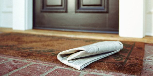 Newspaper on front step of house