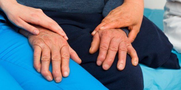 Caring hands of a nurse and doctor for elderly patient with Parkinson's disease.