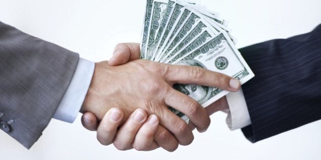 Studio shot of two men shaking hands after making a monetary deal