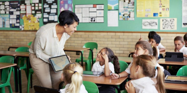 School children in uniforms in class with tablets