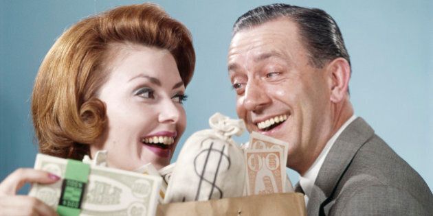 1960s HAPPY COUPLE MAN WOMAN HOLDING SHOPPING BAG FULL OF MONEY LAUGHING LOOKING AT EACH OTHER (Photo by H. Armstrong Roberts/ClassicStock/Getty Images)