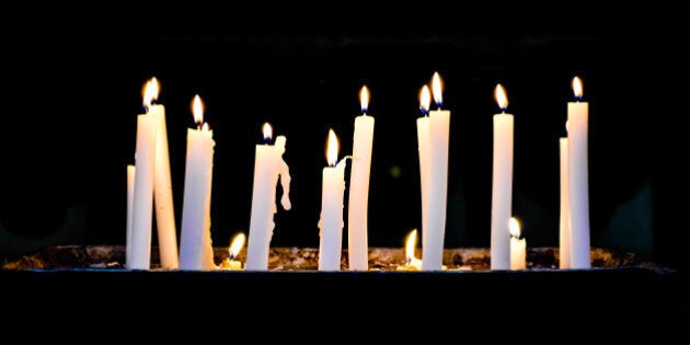 Several candlelights lit up in a row against black background