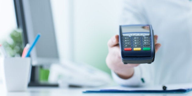 Female pharmacist holding a payment terminal, medical care cost concept