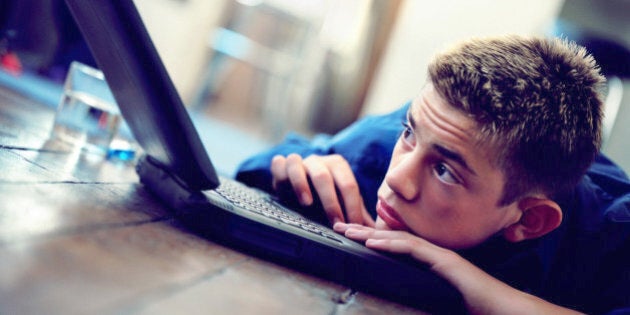 Boy (12-14) resting on laptop