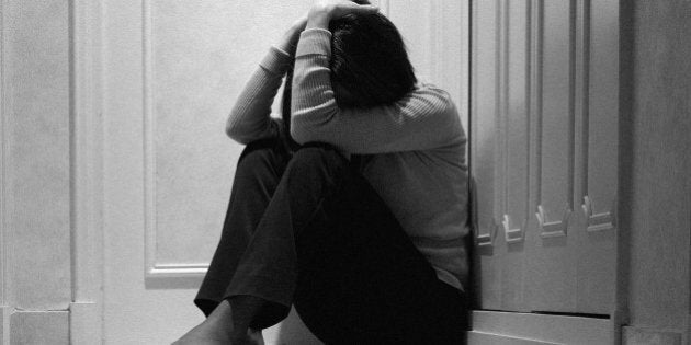 Woman sitting in corridor with head in hands, ground view (B&W)