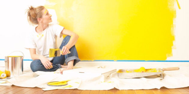 Young woman sitting on the floor , holding a paintbrush